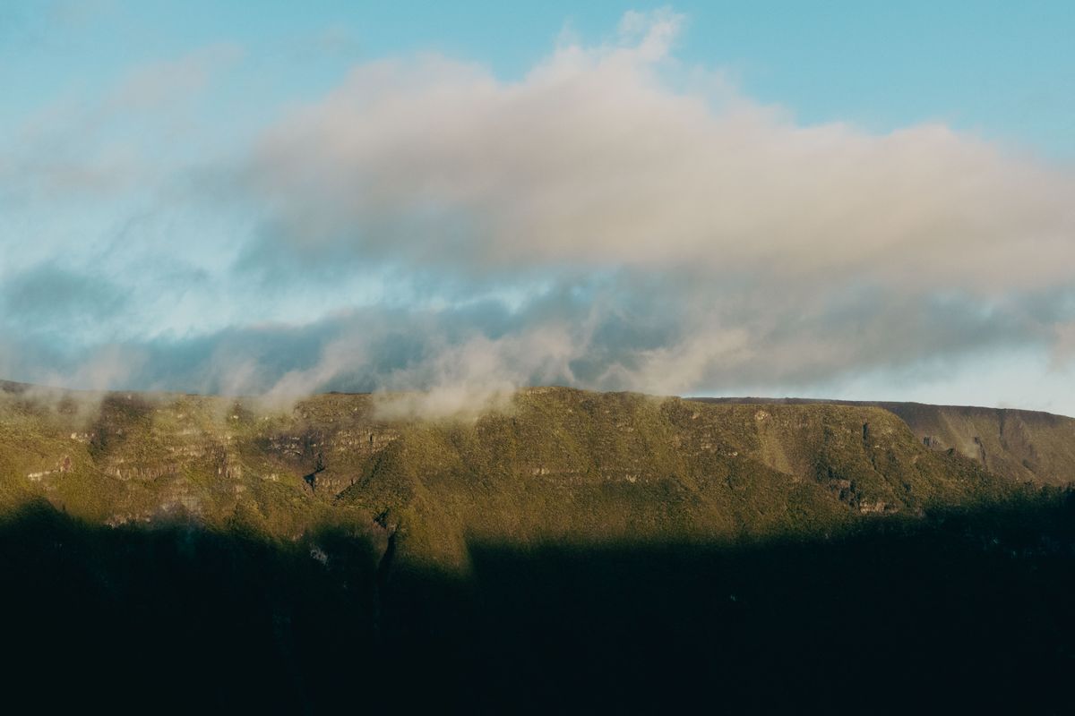 Versant verdoyant du massif du Piton des Neiges dans la brume au lever du jour