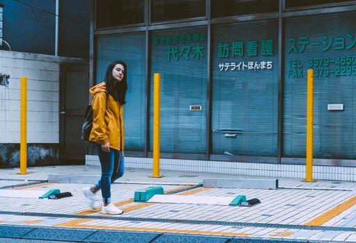 一位时尚女士穿着黄色夹克走过东京街道，为城市景观增添了魅力