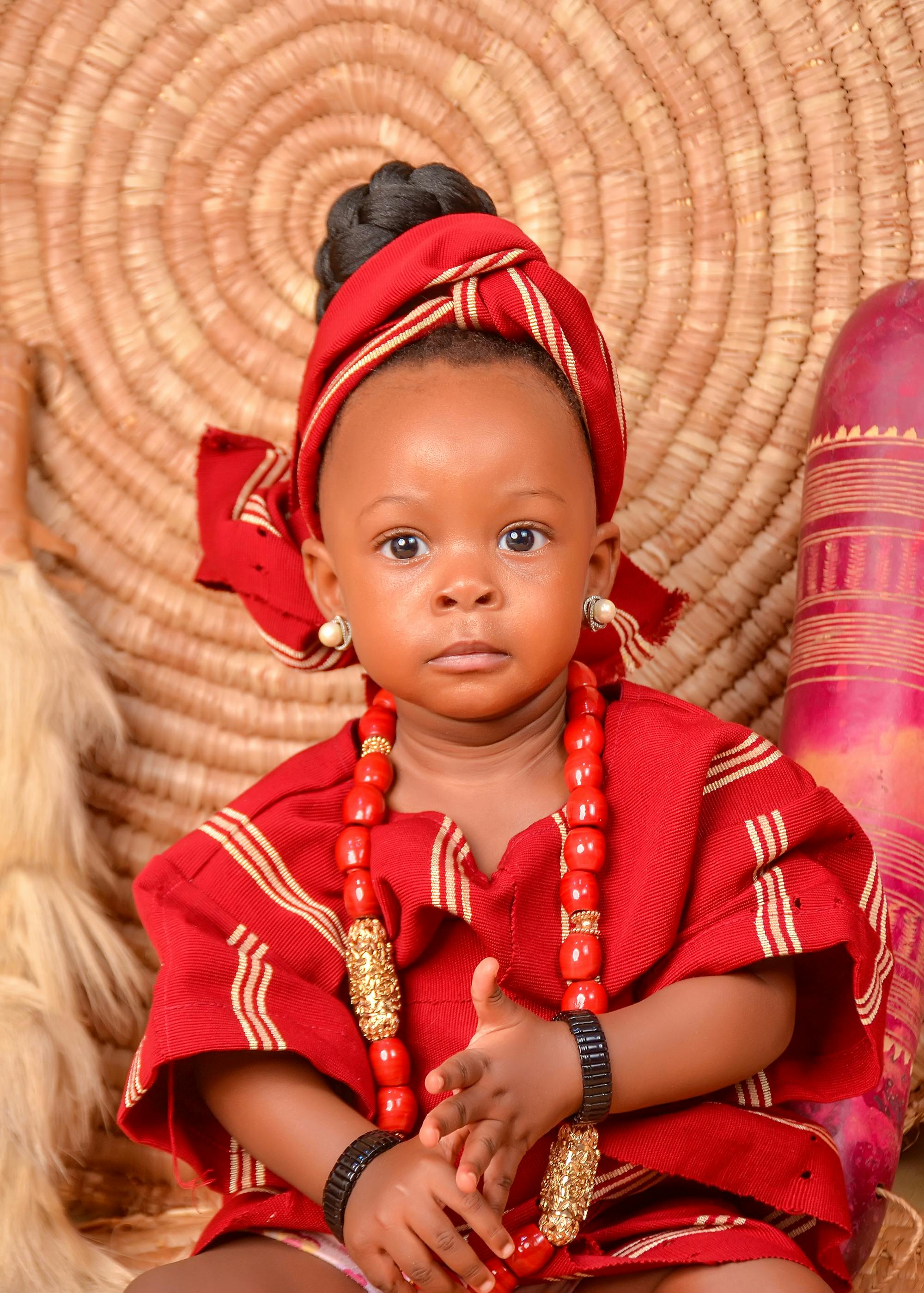 a baby in a red outfit sitting on a rug