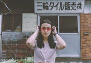 一位戴着眼镜的时尚年轻女子自信地站在东京市区的街道上