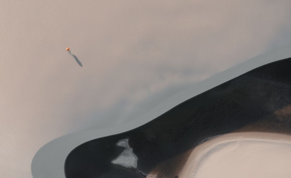 Aerial photo of a single person walking on expansive sand dunes in São Luís, Brazil.