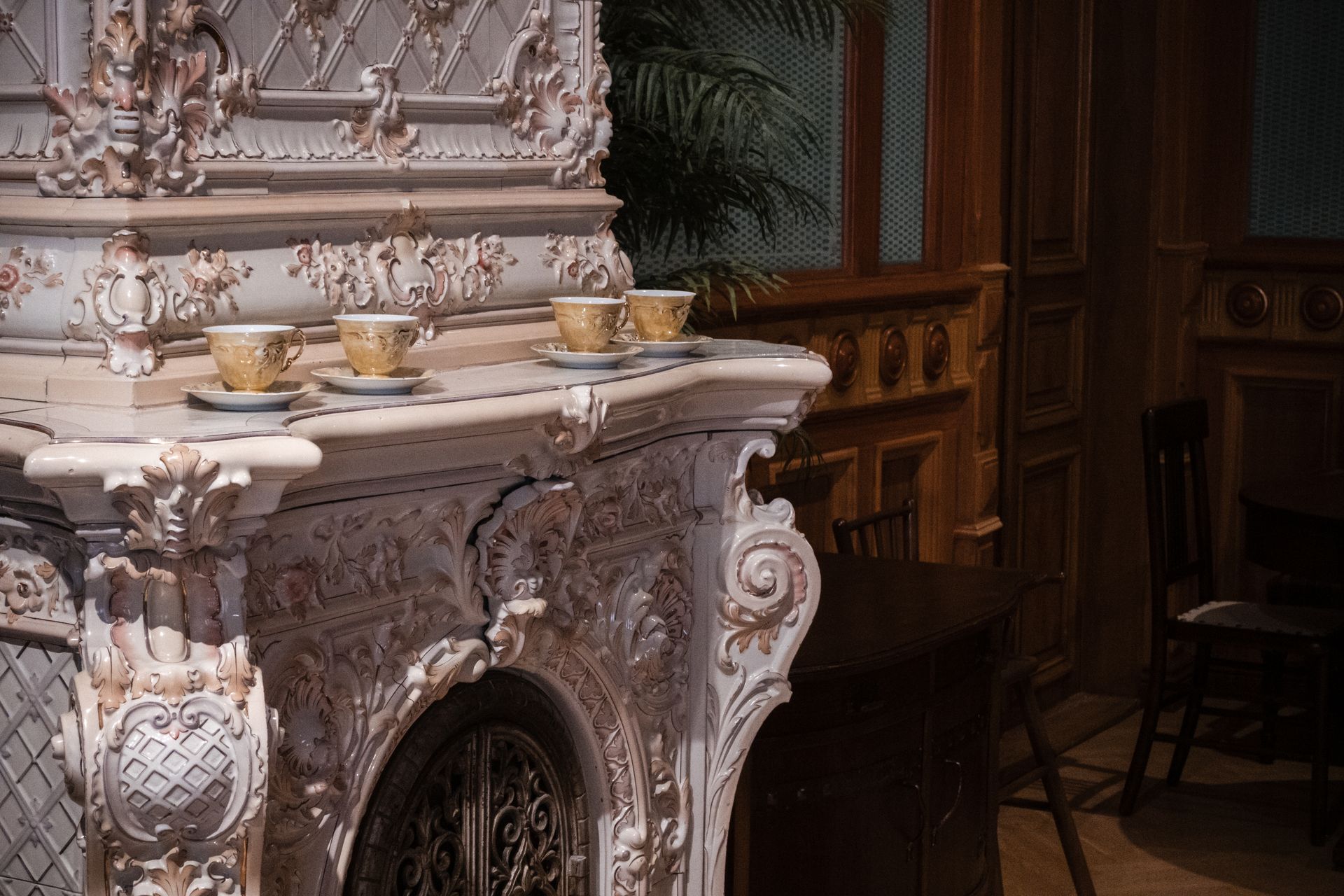 Ornate baroque-style ceramic fireplace with teacups in a classical Finnish interior.