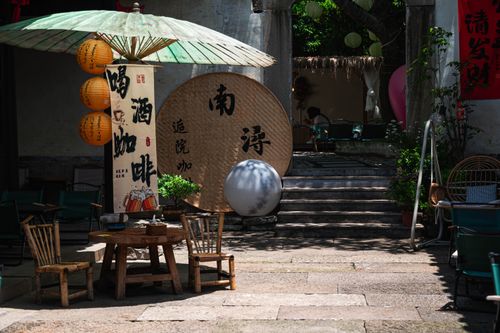 Free Serene outdoor seating with traditional Asian decor, lanterns, and green umbrella. Stock Photo