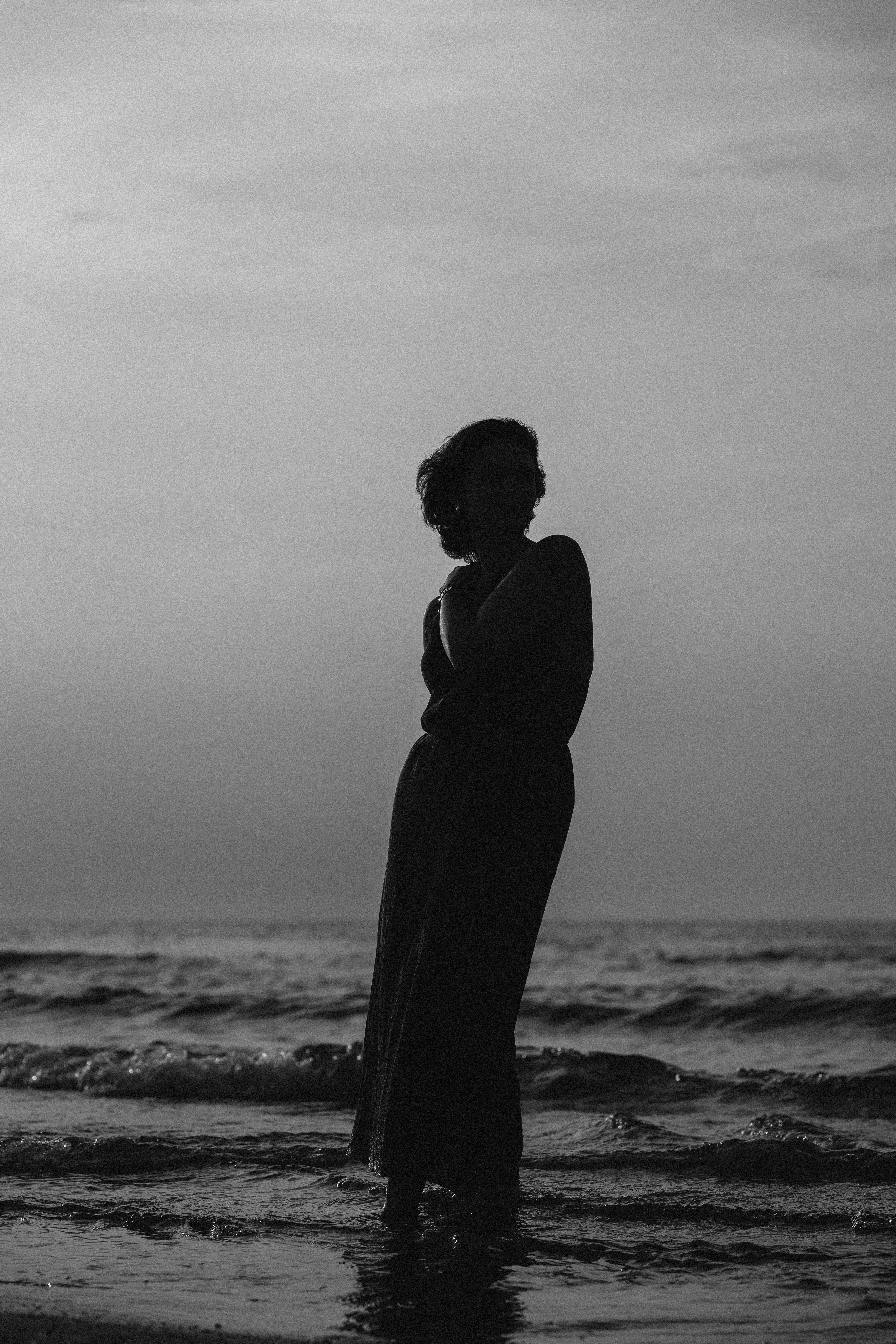 A woman standing on the beach in silhouette · Free Stock Photo