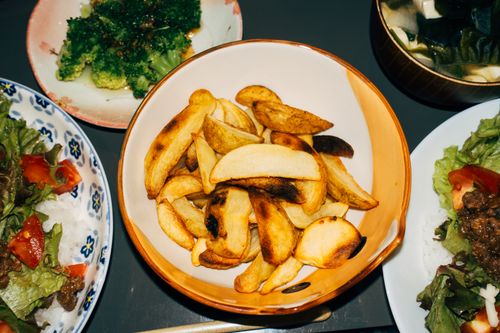 Free Delicious meal featuring crispy potato wedges, fresh salads, and vibrant broccoli sides. Stock Photo