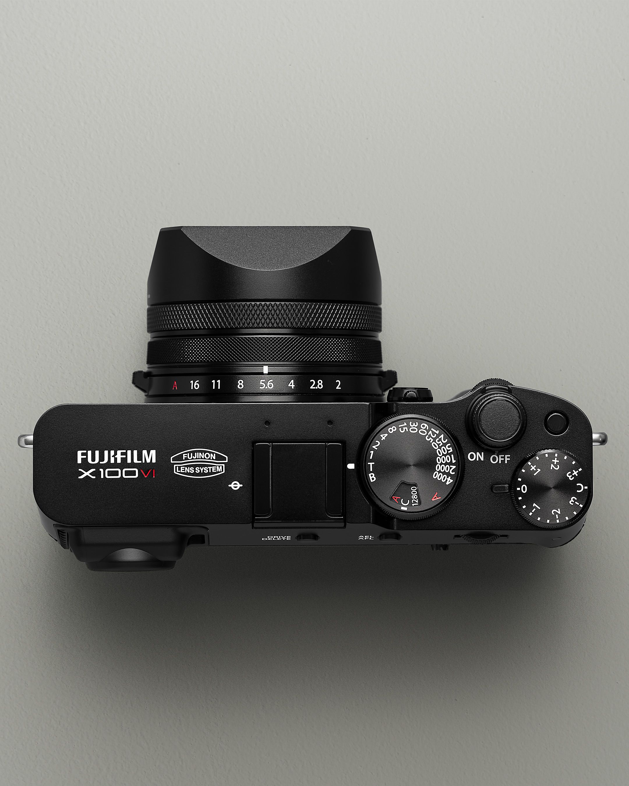Minimalistisch bovenaanzicht van een moderne Fujifilm X100V camera tegen een neutrale achtergrond.