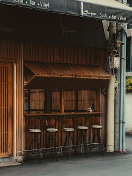 A quaint sushi bar with bamboo décor and bar stools in an urban setting, offering a cozy ambiance.