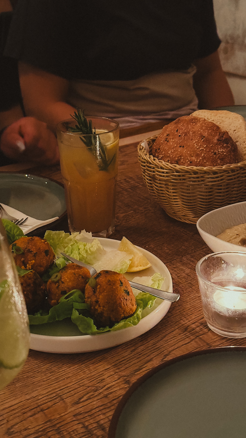 Free Warm, inviting dinner scene featuring falafel, bread, and a refreshing beverage on a rustic table. Stock Photo