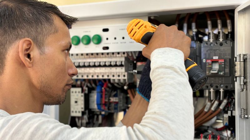 A homeowner inspecting an electrical panel breaker box in a garage