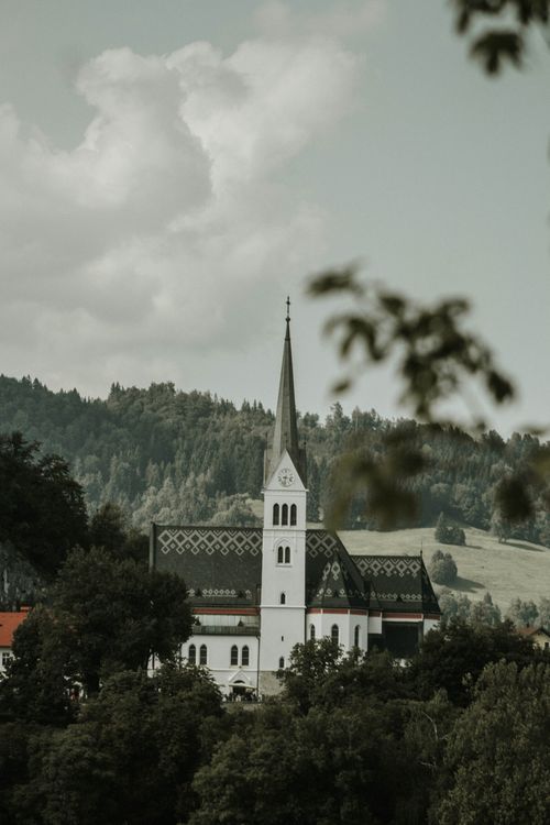 Free A picturesque church nestled in the lush Slovenian landscape, showcasing classic architecture and serene surroundings. Stock Photo