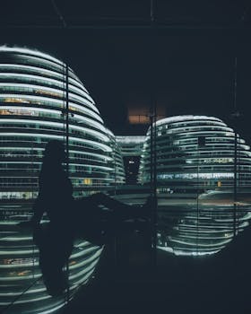 夜晚，一名女性的戏剧性轮廓出现在现代化、明亮的建筑前