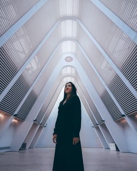 一位妇女站在未来派设计的现代建筑空间中