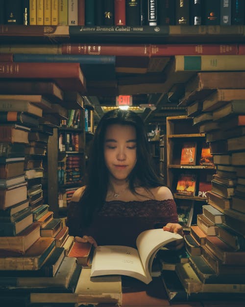 Girl reads book under archway made of books