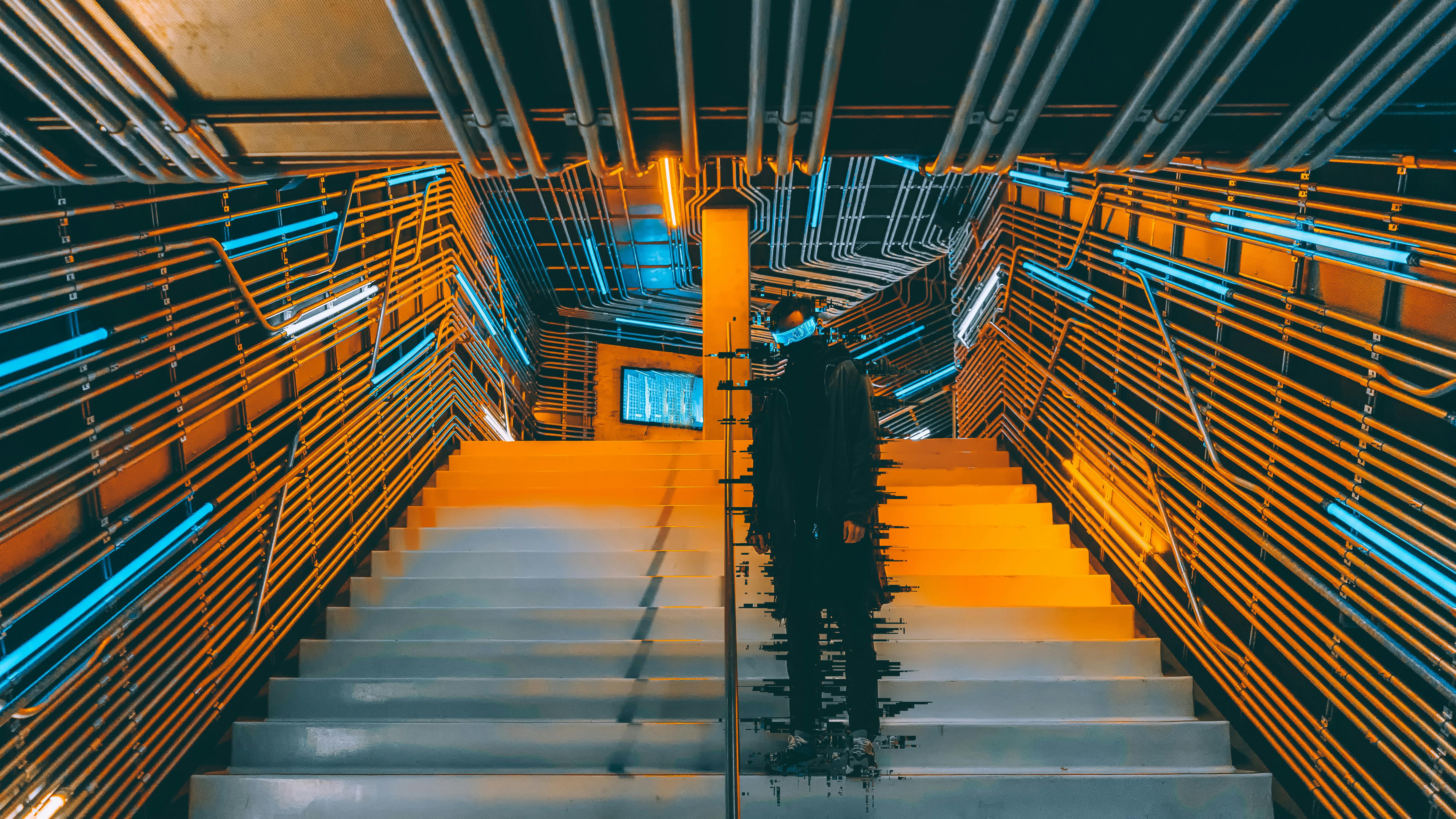 一个人站在未来派的楼梯上，四周被霓虹灯和金属墙壁包围