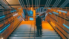 一个人站在未来派的楼梯上，四周被霓虹灯和金属墙壁包围