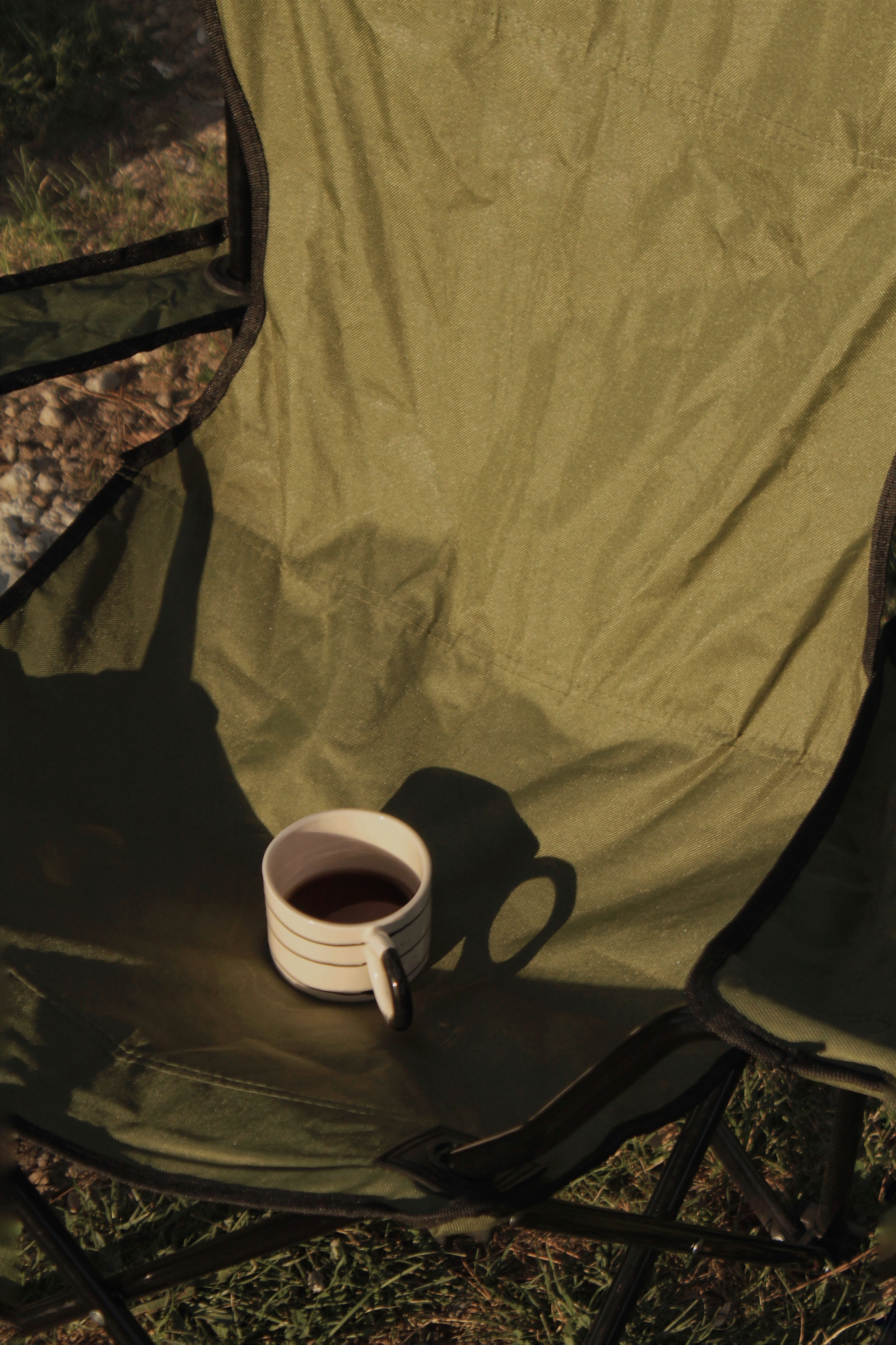 Mug of coffee on a camping chair in morning light