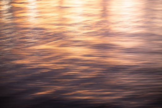 A serene abstract view of golden sunset reflections dancing on gentle water ripples.