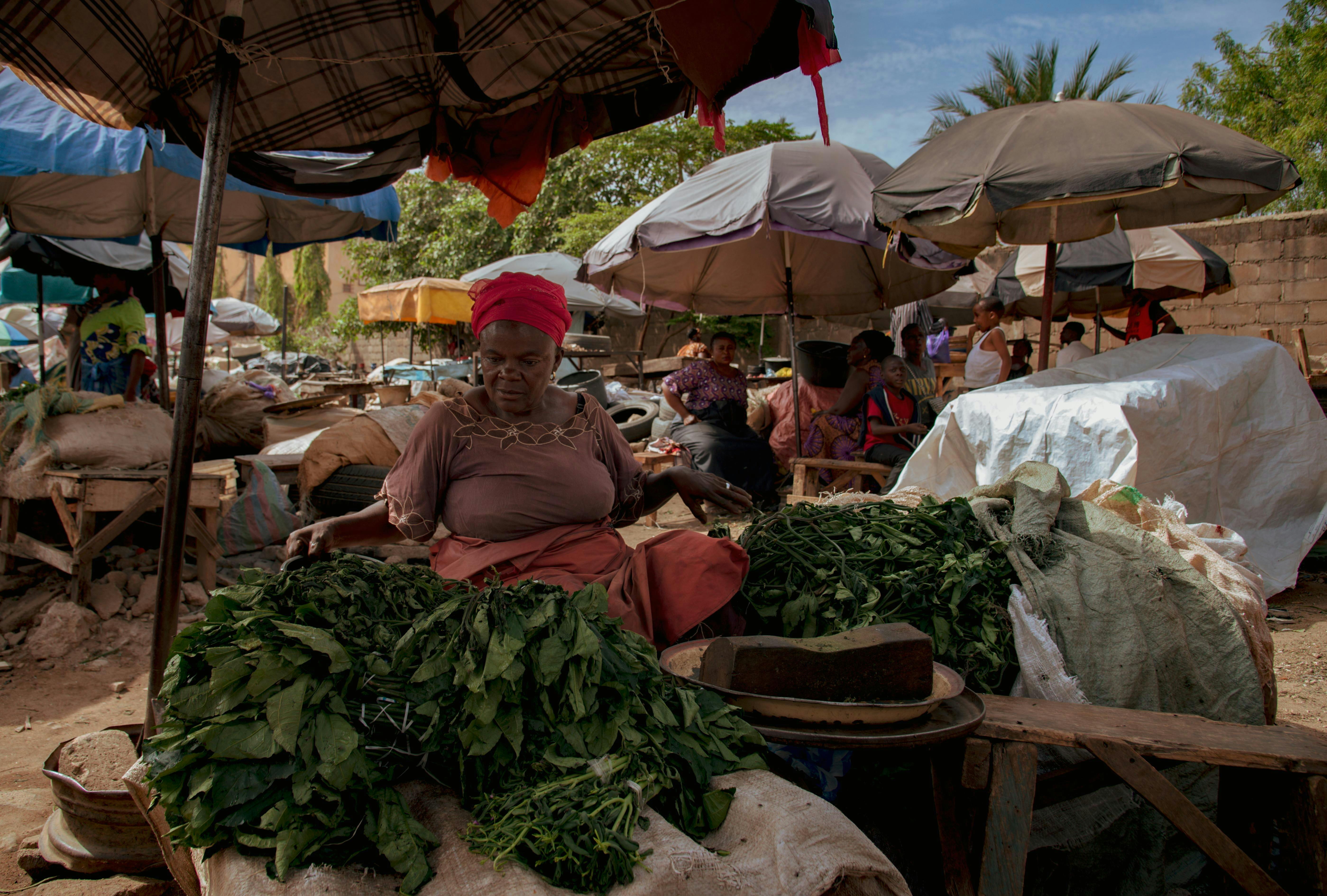 a woman selling vegetables at an outdoor market