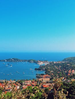A vibrant aerial view of a Mediterranean coastal town with clear blue waters and lush greenery.