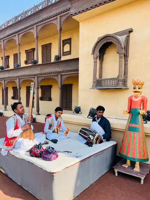 Free A group of musicians playing traditional instruments in front of historic Indian architecture. Stock Photo