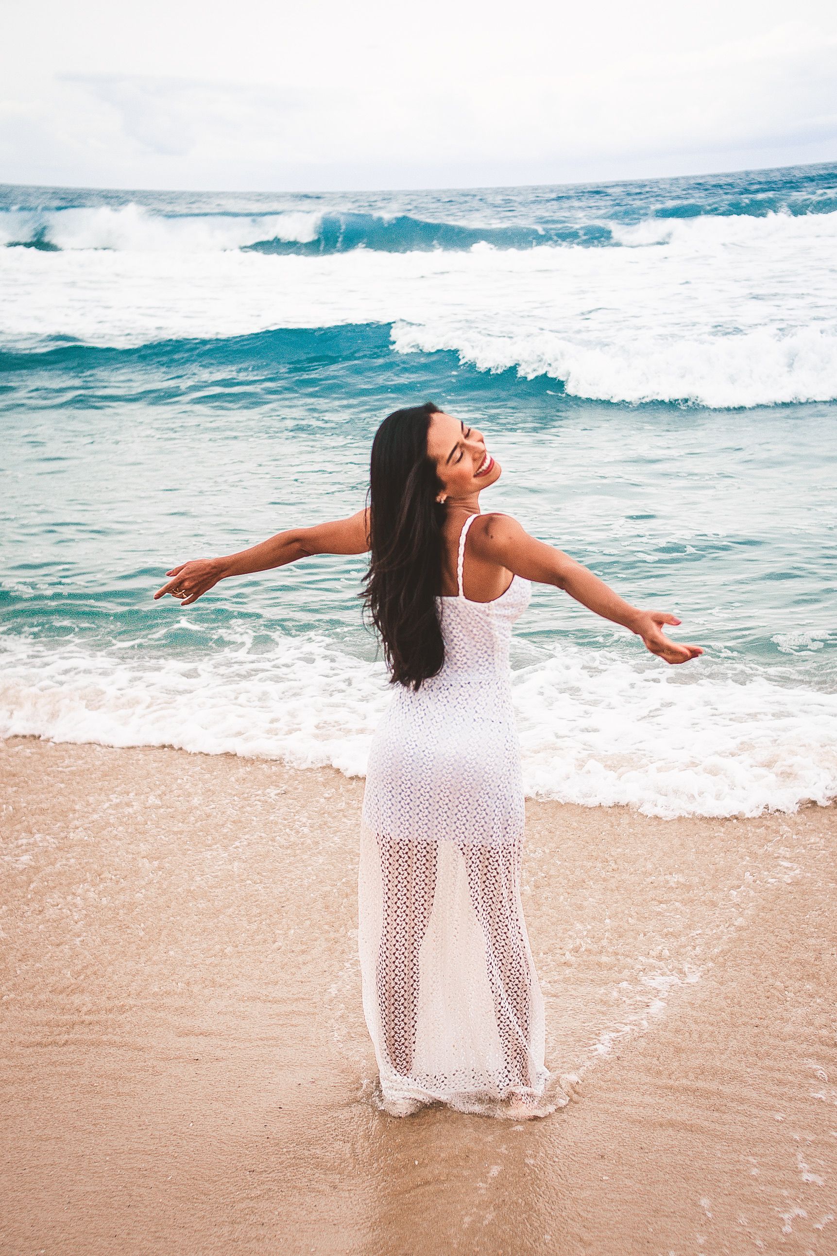 A woman in a white dress is standing on the beach · Free Stock Photo
