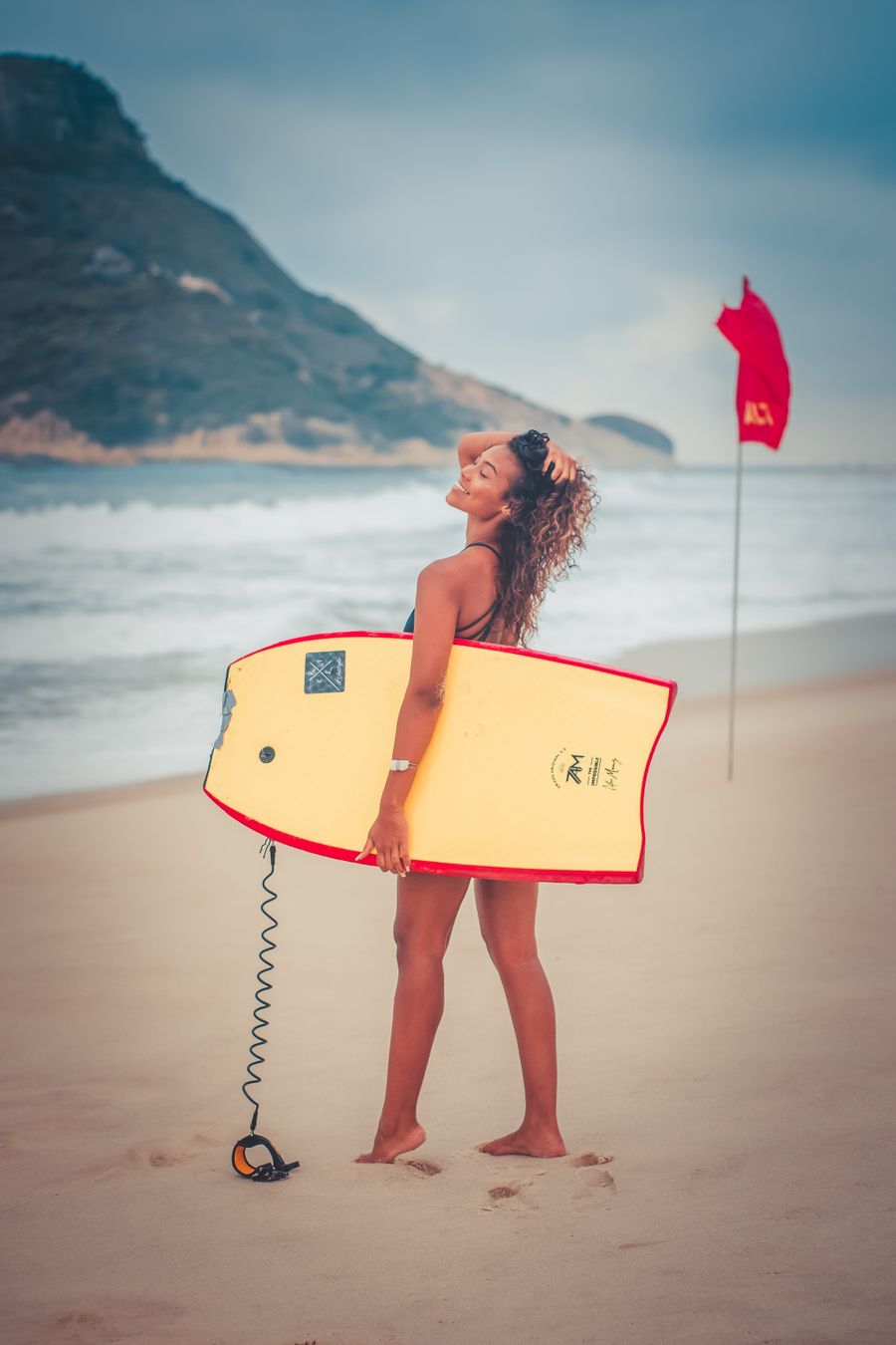 Young woman holding a bodyboard on a tropical beach