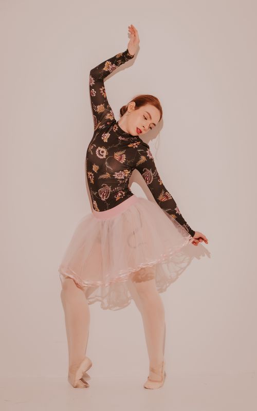 Free A young ballerina elegantly poses in a floral costume, exuding grace and beauty, indoors. Stock Photo