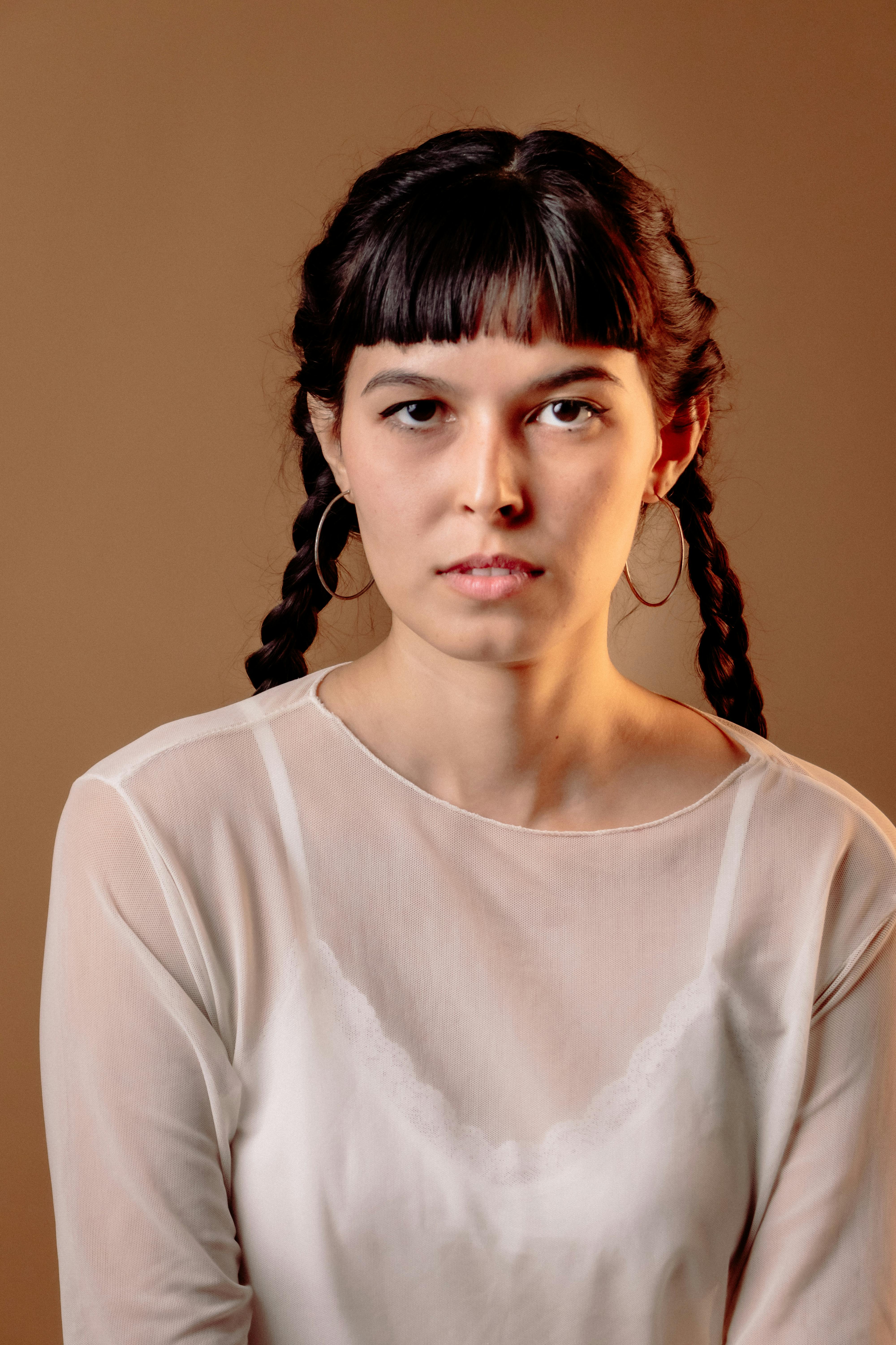 Serene portrait of a woman with braids in a chic white top, showcasing elegance.