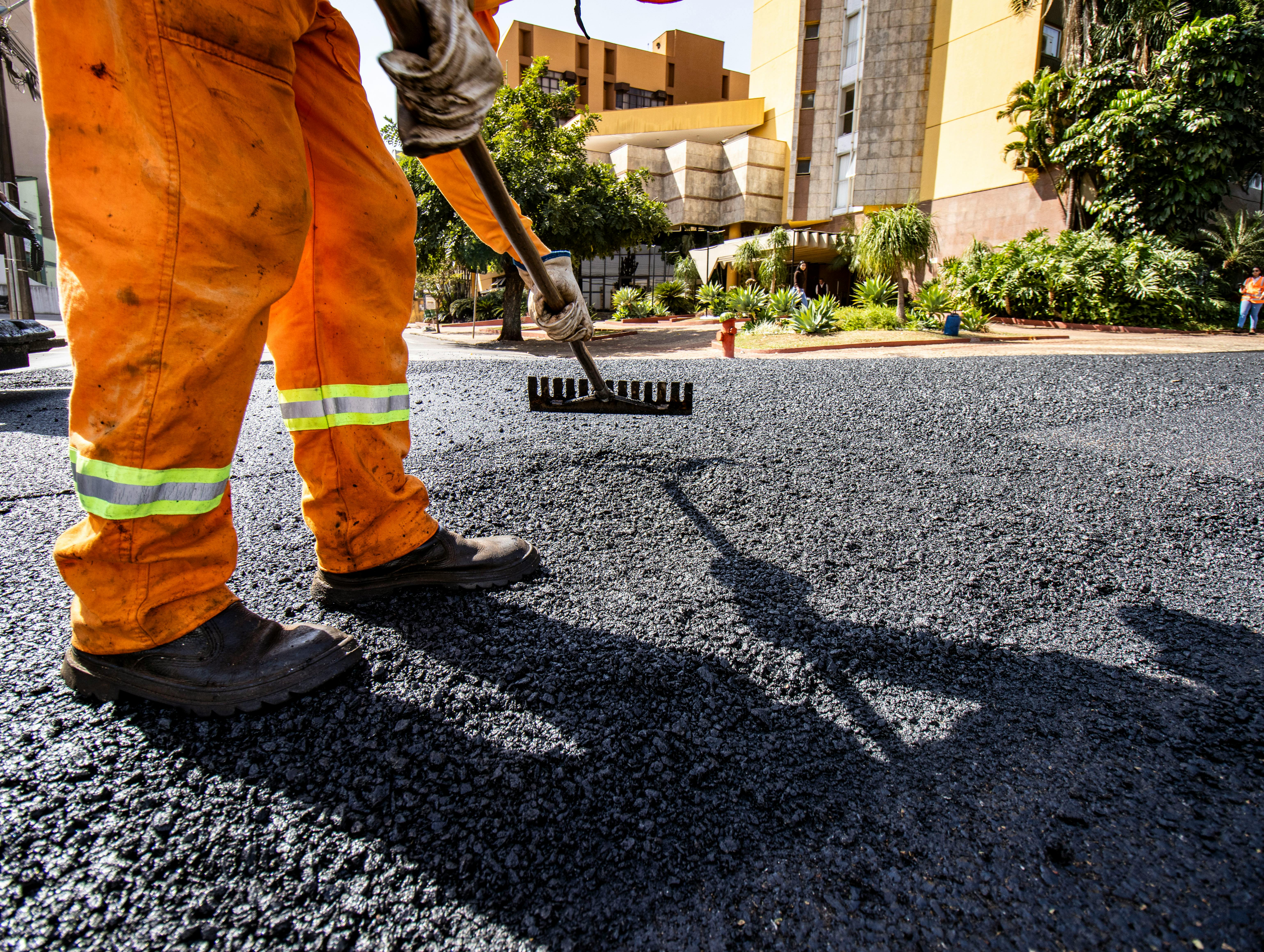 Worker in orange gear paving a road in Londrina city during daytime.