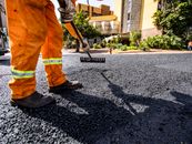 Worker in orange gear paving a road in Londrina city during daytime.