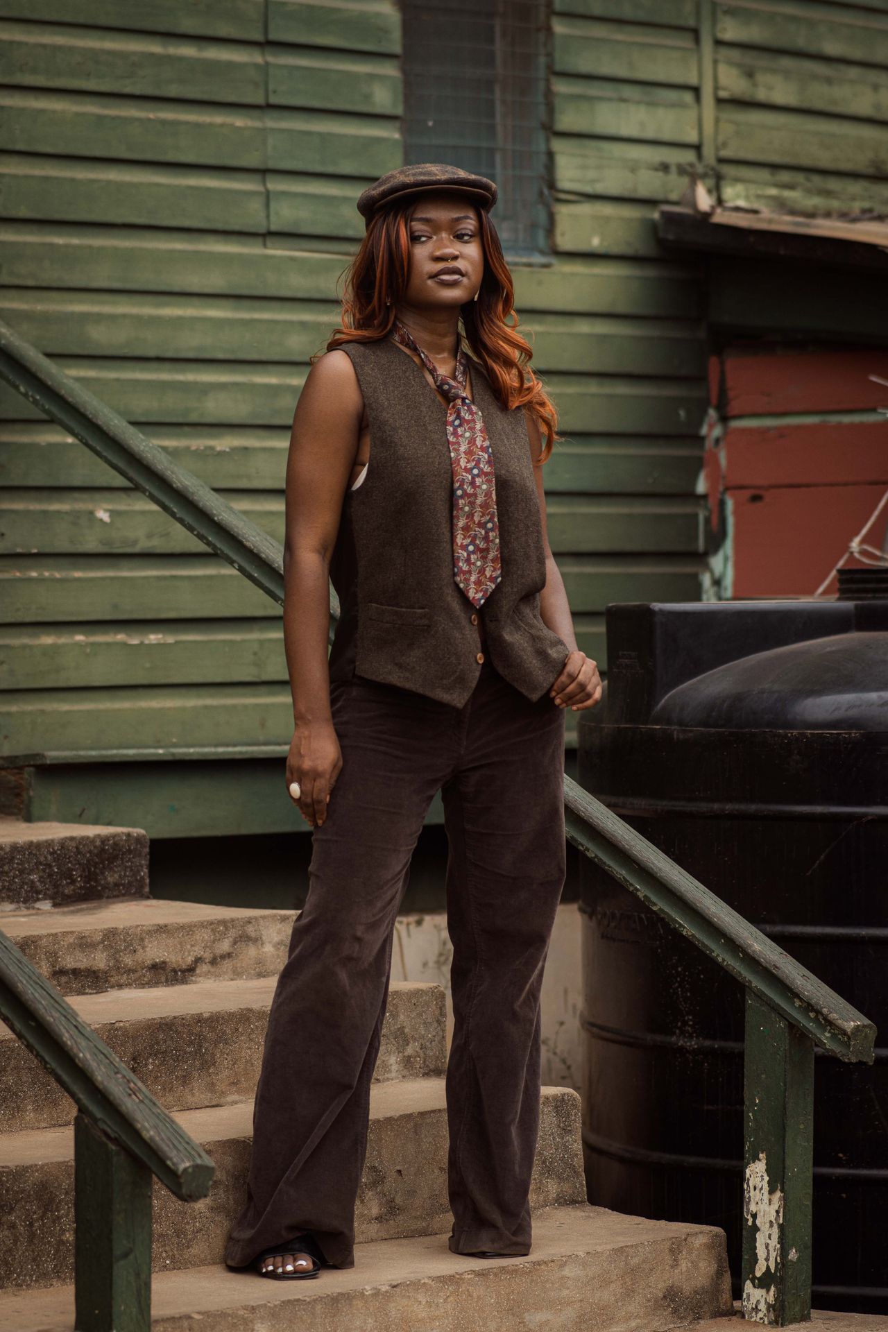 Woman in a brown vest, tie and wide-leg pants on outdoor steps