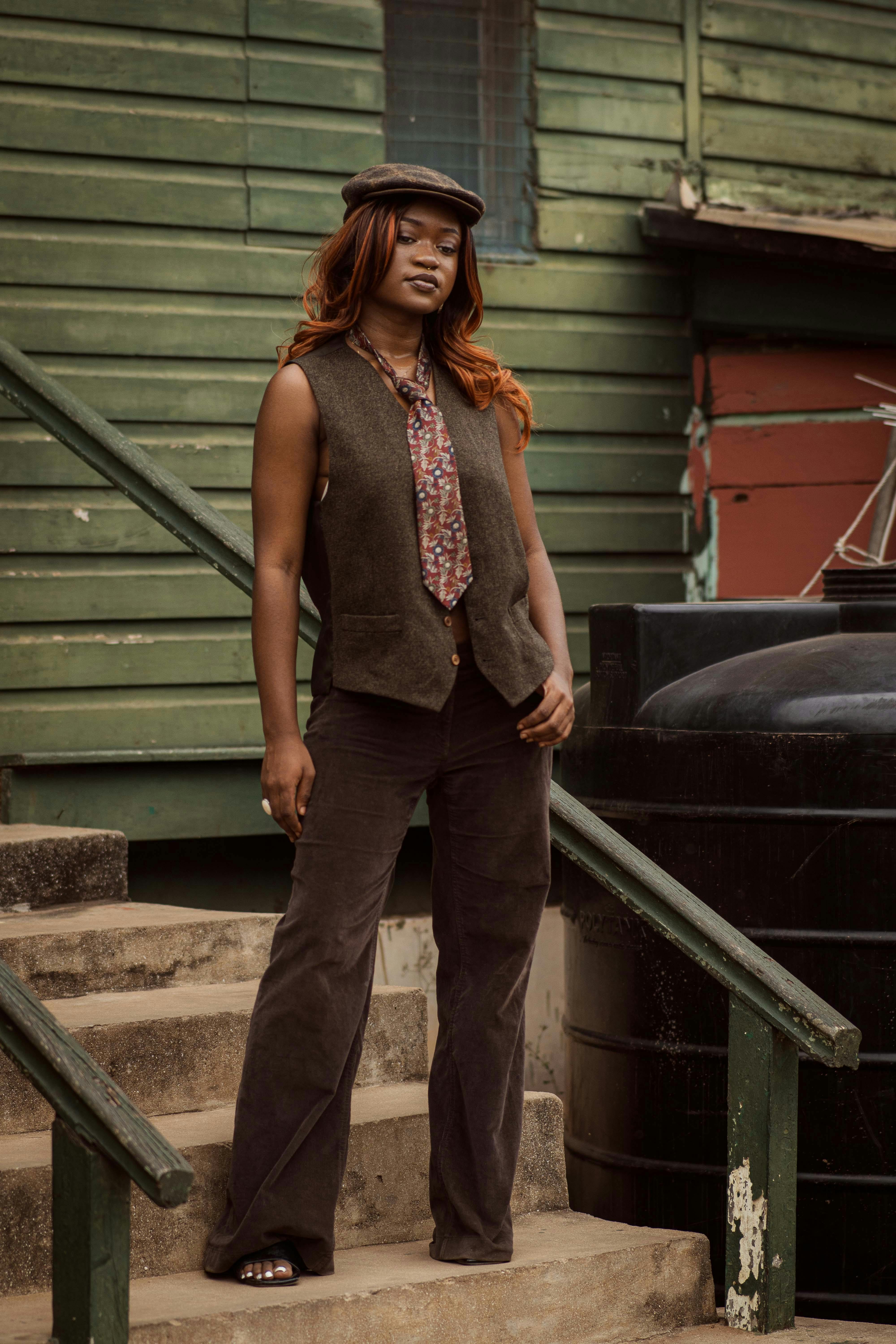 a woman in a hat and vest standing on steps