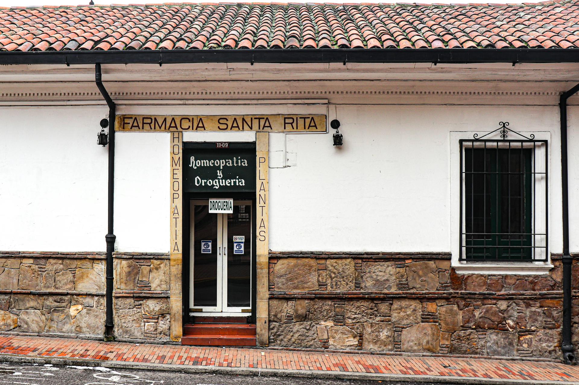 Exterior view of a vintage pharmacy with a classic stone wall facade and tiled roof.