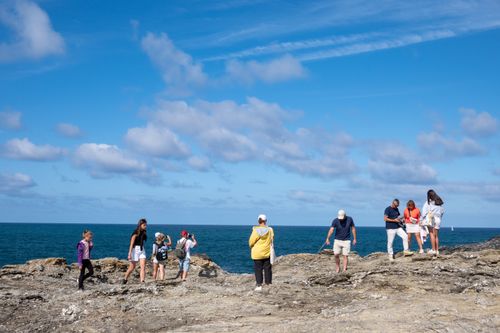 Free A group of visitors enjoying a sunny day on a coastal cliff with a beautiful ocean view. Stock Photo