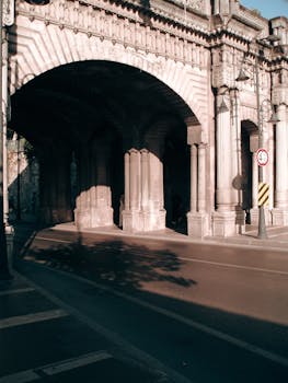 A classic stone archway casting shadows over an empty city street.