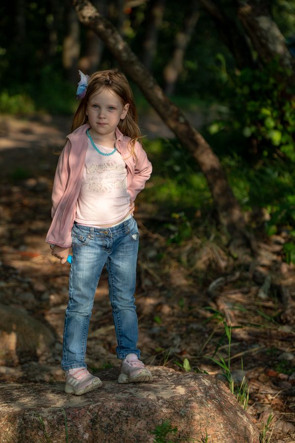 A little girl sitting on the rocks in a dress · Free Stock Photo