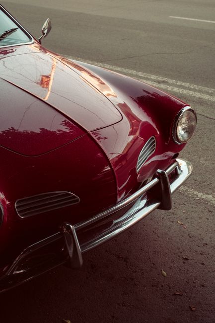 Close-up of a classic red convertible car showcasing chrome details and vintage design.