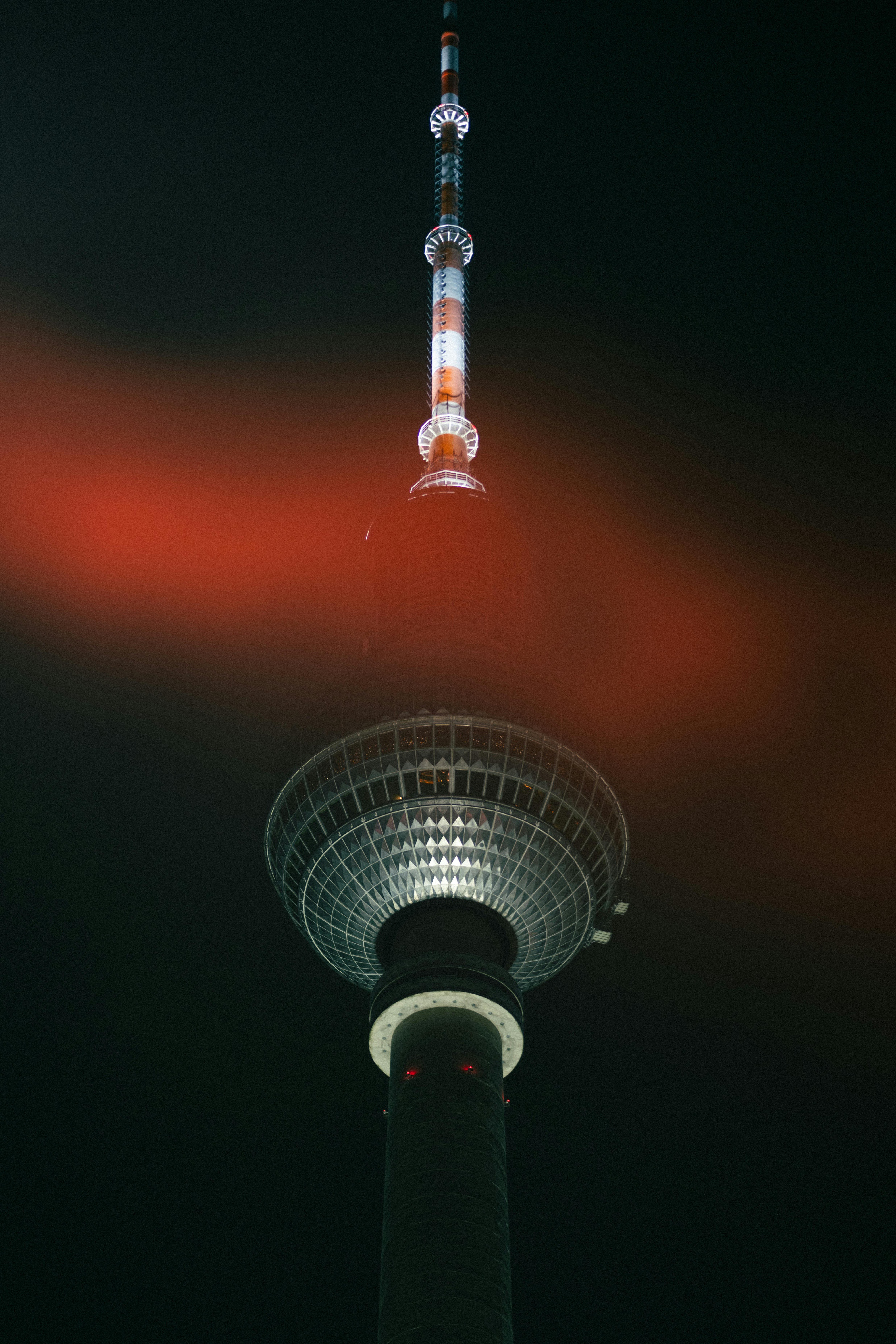 Striking view of the Berlin TV Tower with vibrant red illumination in a dark night sky.