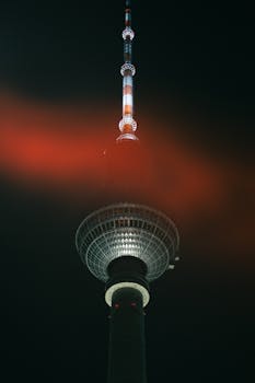 Striking view of the Berlin TV Tower with vibrant red illumination in a dark night sky.