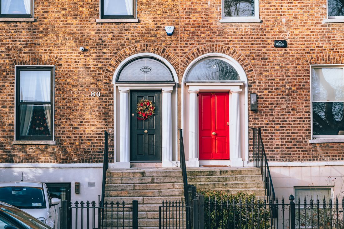Classic brick facade with a bold red door and a decorated black door