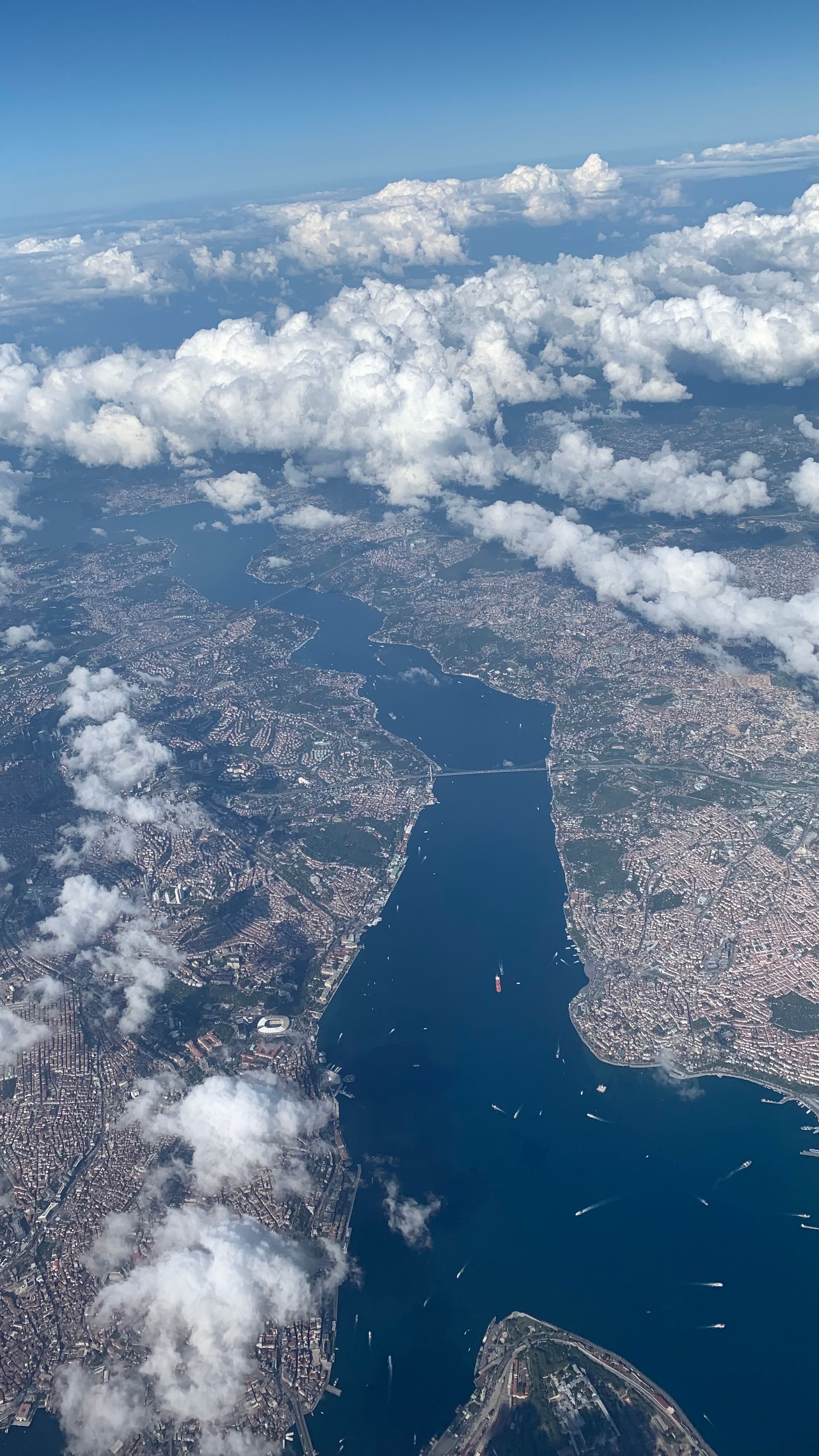 A stunning aerial perspective of the Bosphorus Strait surrounded by urban landscape and clouds.