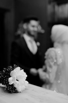 Classic black and white photo of wedding bouquet with bride and groom in soft focus. - Fotografer Sidoarjo