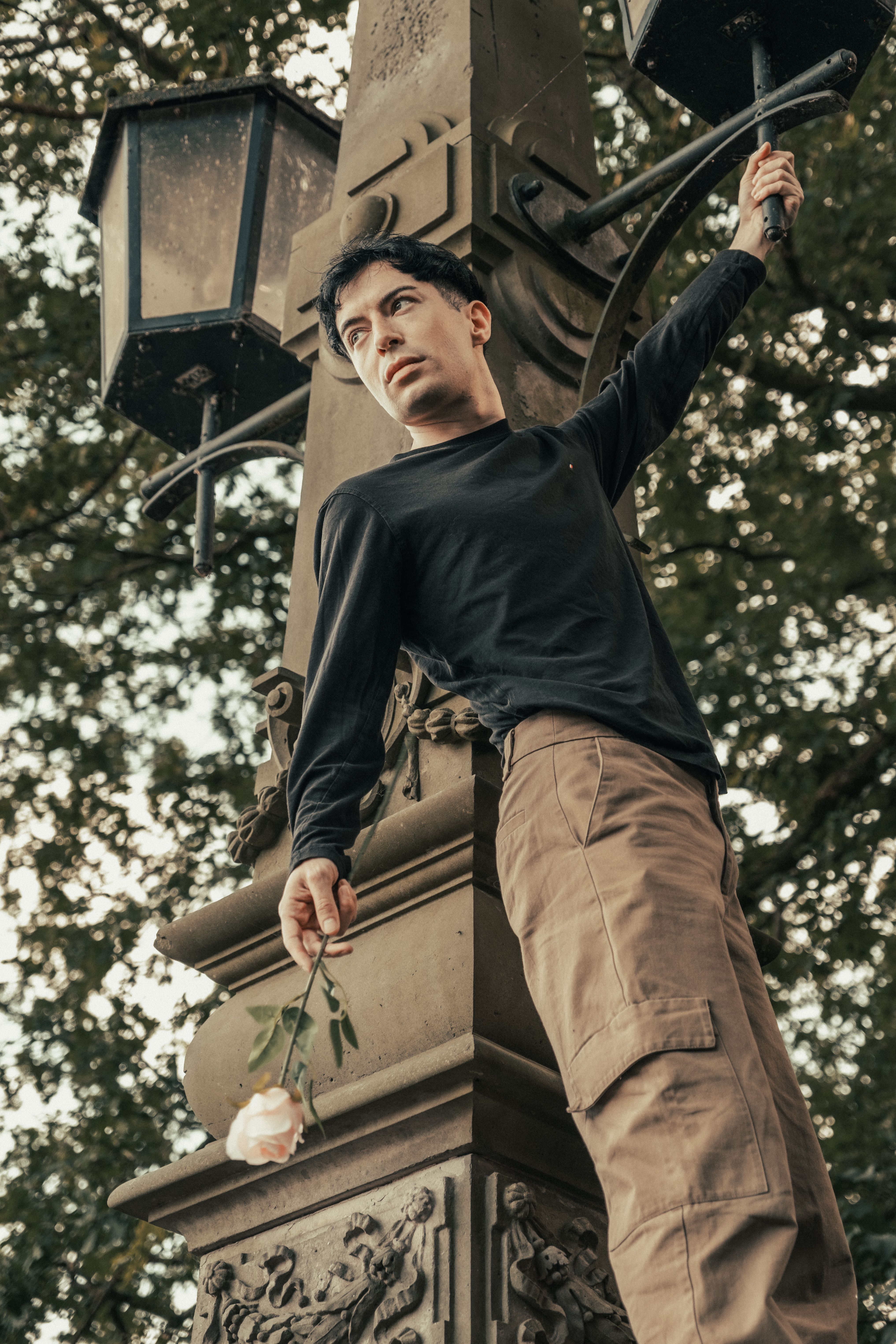 A man is leaning on a lamp post with a rose · Free Stock Photo