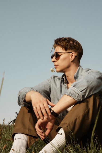 Stylish man sitting outdoors on a sunny day, enjoying nature and relaxation.