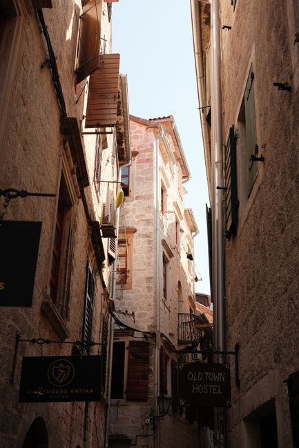 Explore a quaint narrow alleyway with rustic stone buildings and signs in a classic European town.