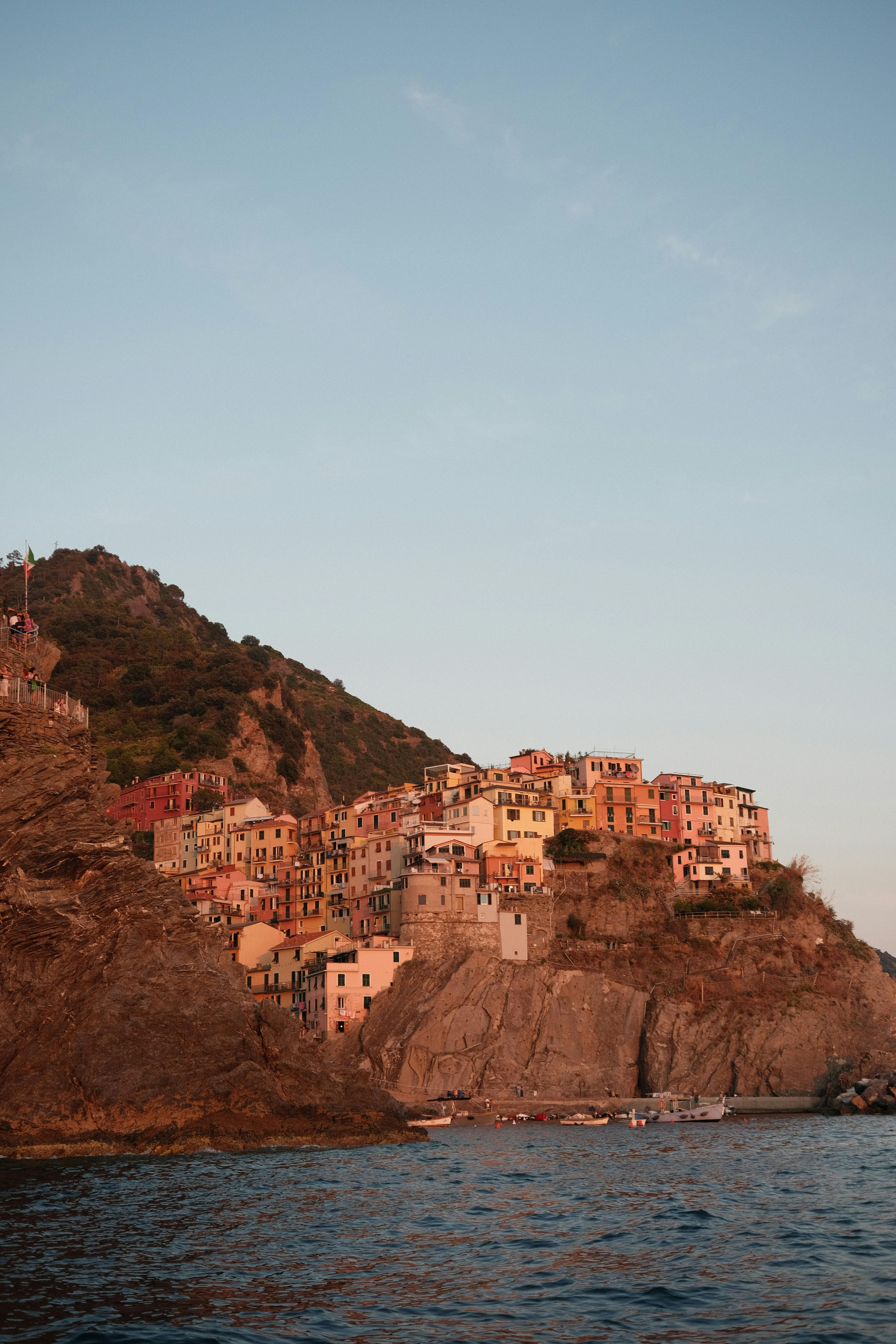 Charming coastal village on a cliff overlooks the sea under a sunset sky. Perfect travel destination.