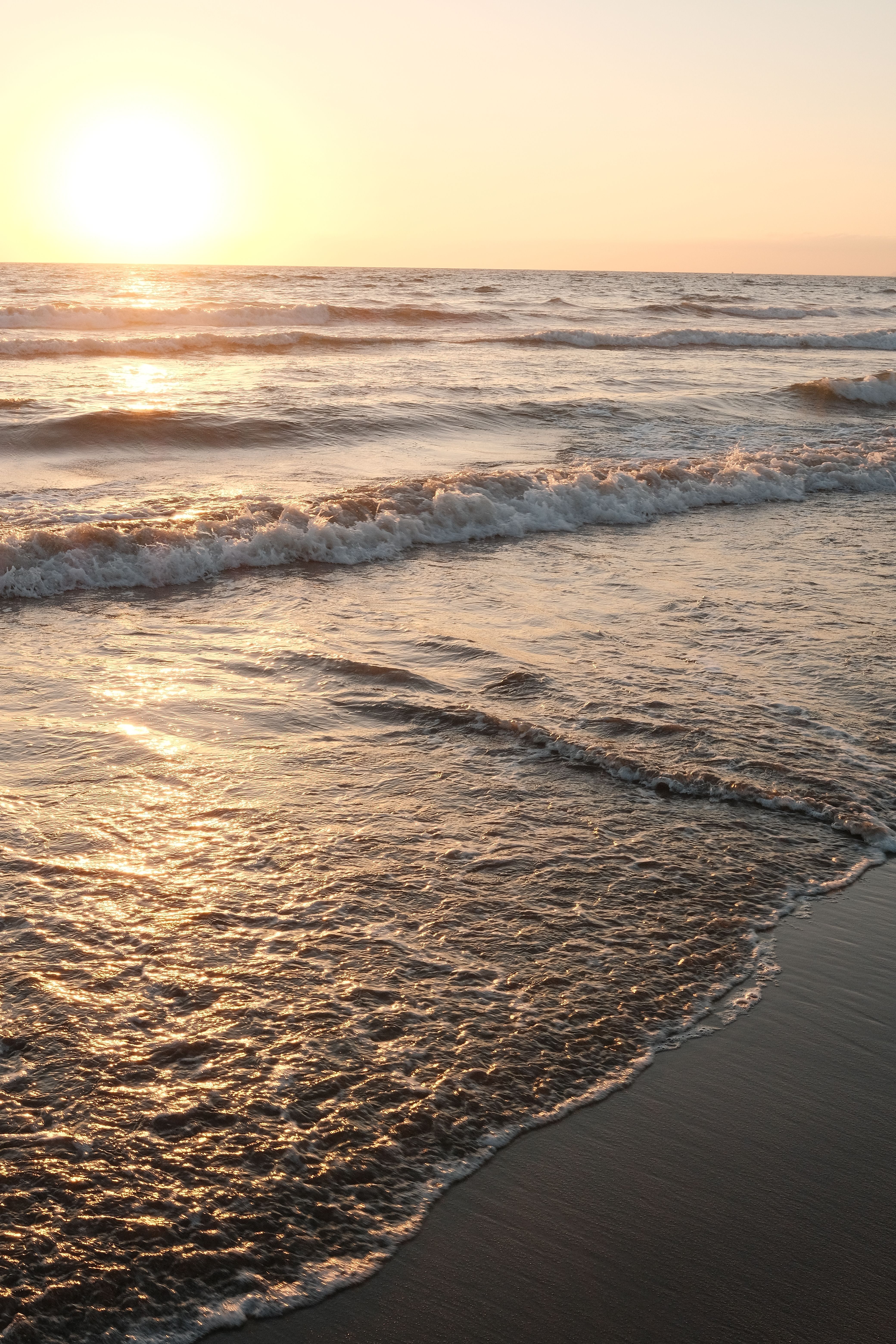 A sunset on the beach with waves and sand · Free Stock Photo