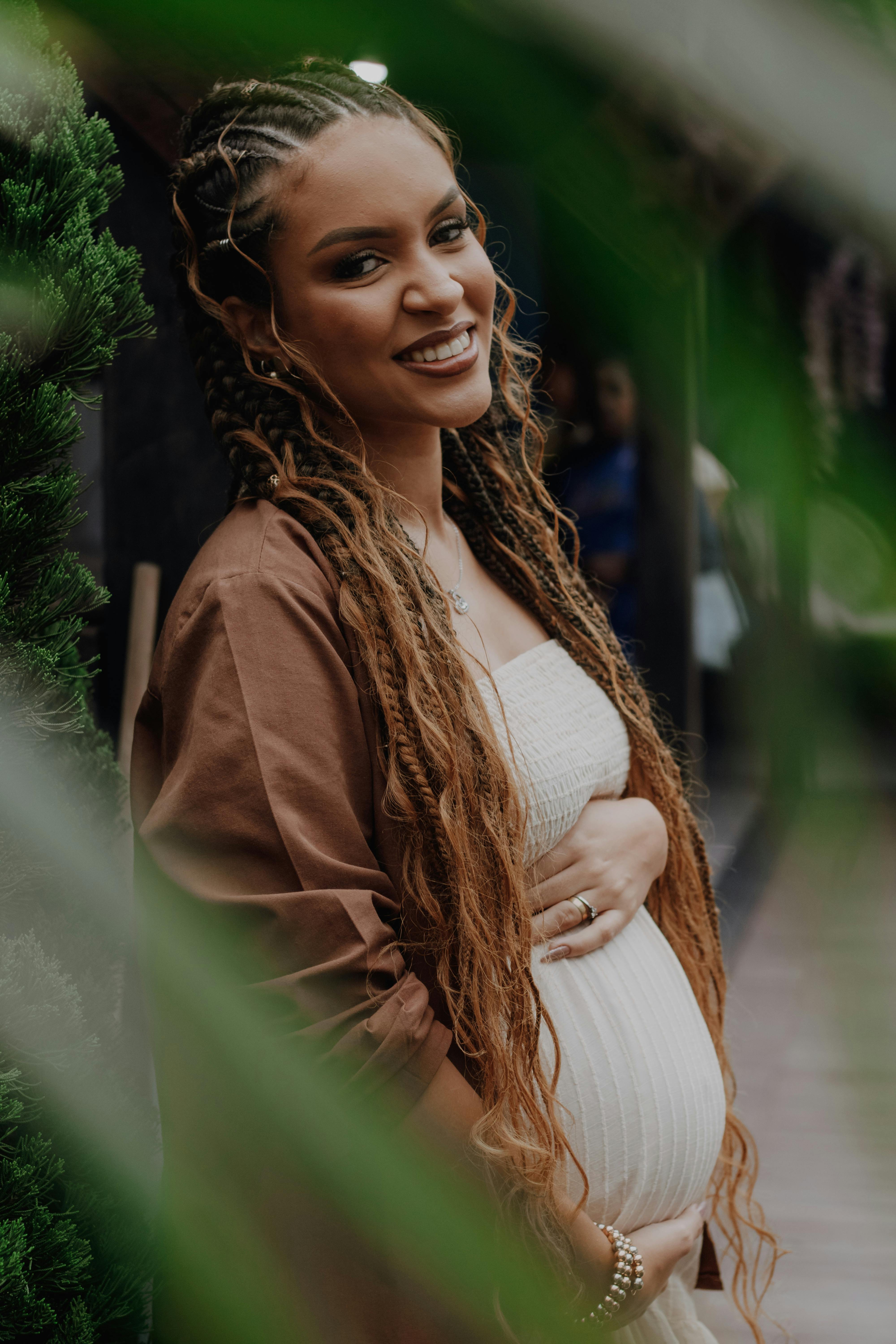 a pregnant woman with dreadlocks is smiling