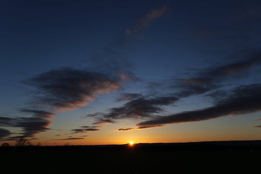 Serene sunset scene with dramatic clouds silhouetted against the sky.
