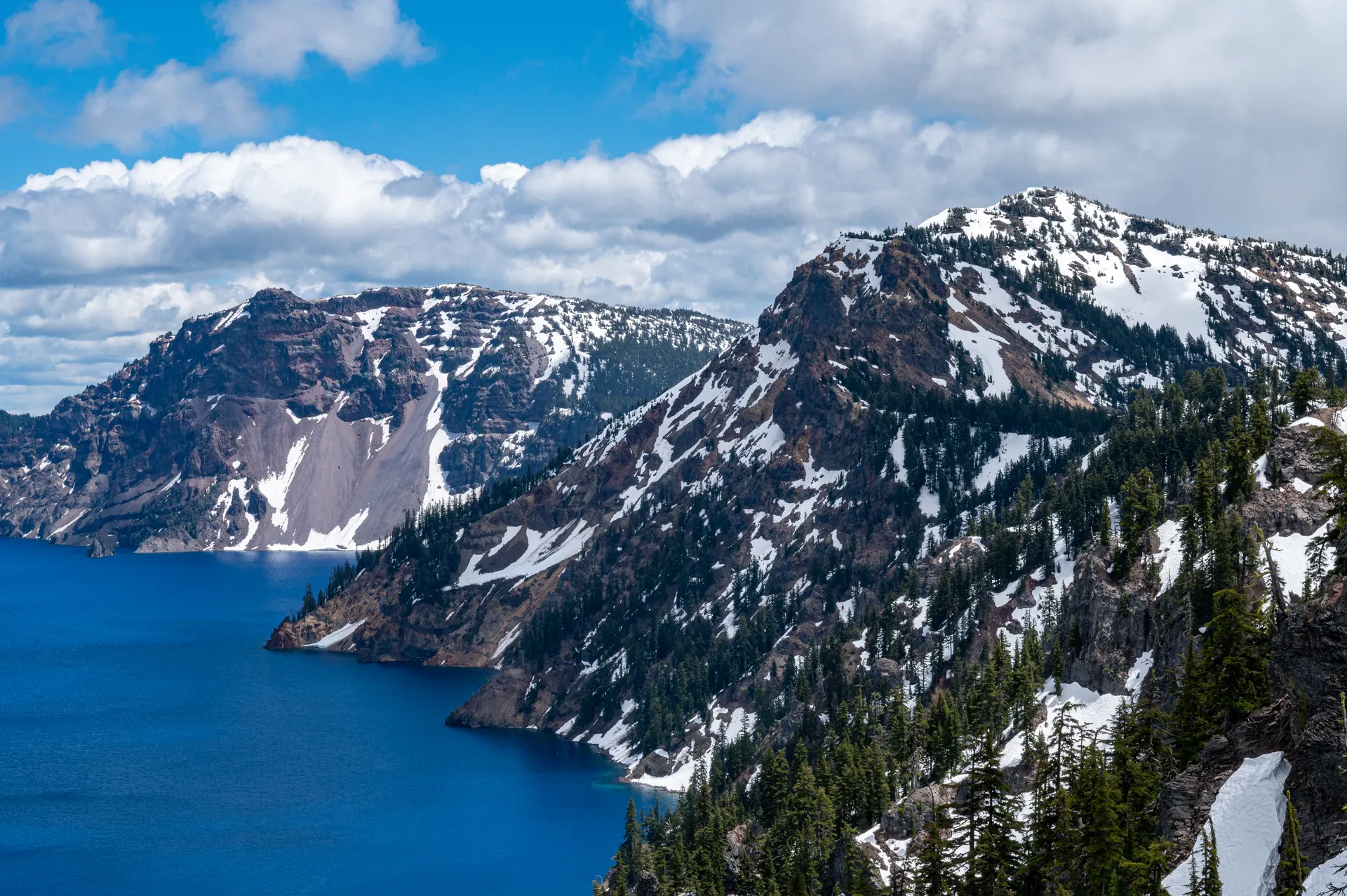 Snow-capped mountains overlooking Crater Lake under a blue sky. Snow-capped mountains overlooking Crater Lake under a blue sky.